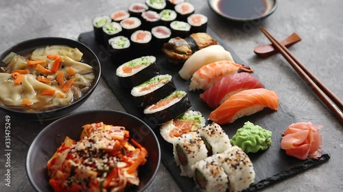 不同种类的寿司卷放在黑色石板上