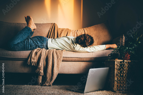 无聊的女人孤独地躺在沙发上。因感染冠状病毒被隔离的妇女在h工作