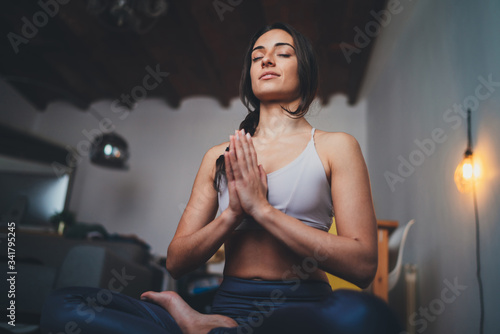 年轻健康美丽的女人在运动上衣和打底裤练习瑜伽坐在莲花