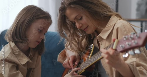 童年和母亲的快乐时刻，一位女士在教女儿弹吉他