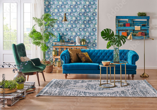 蓝色的壁纸和沙发风格的家具，装饰木质调色板书架，金色的灯和中间的t
