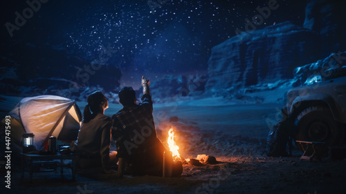 快乐的夫妇自然露营在峡谷，坐在一起看篝火，聊天，看黑